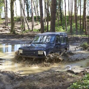 Landrover driving through water in woodland