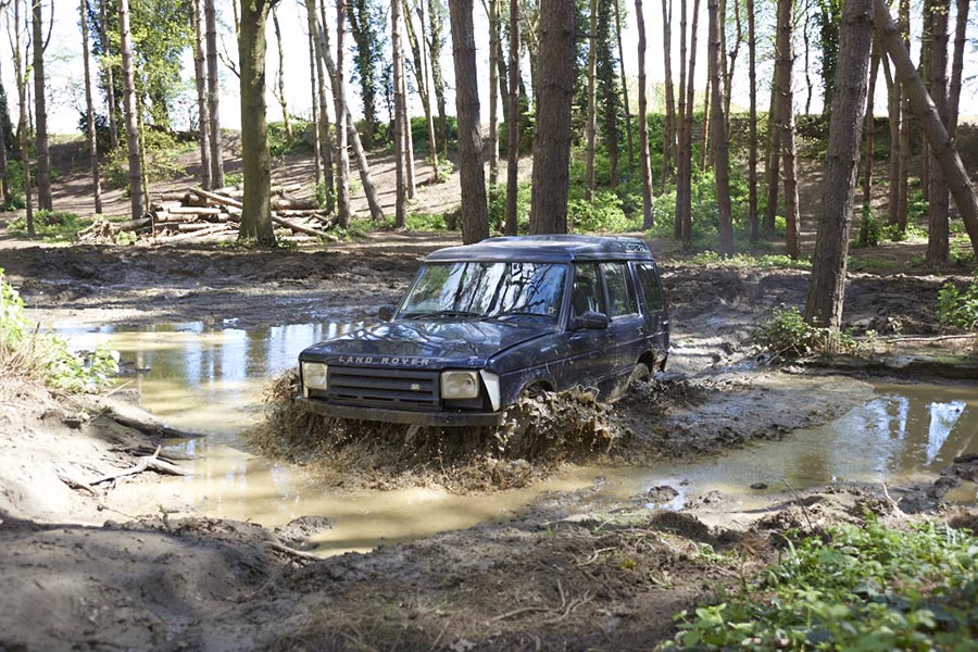 Landrover driving through water in woodland